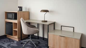 A compact workspace with a desk, chair, and a microwave above a cabinet.