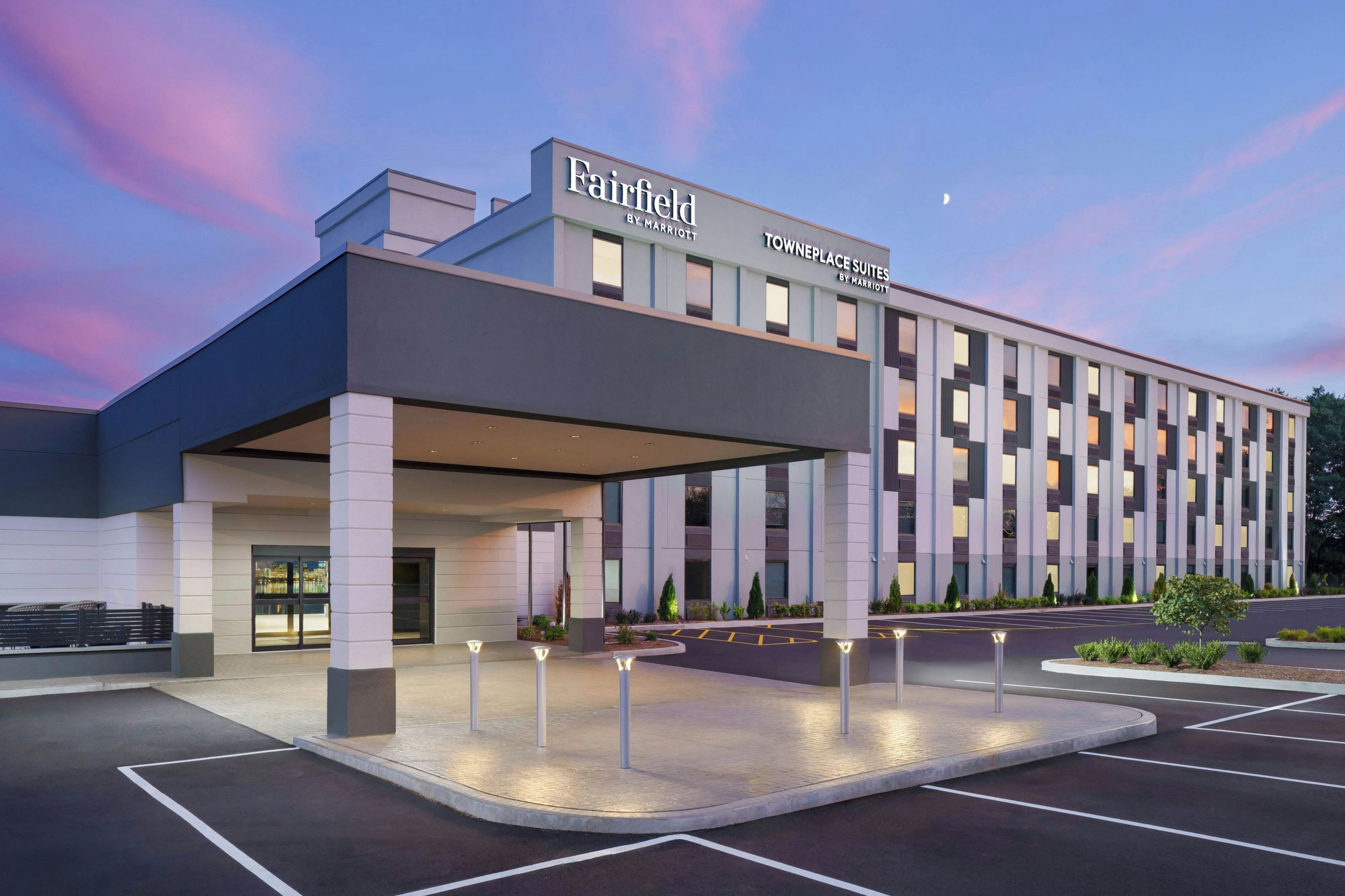 A modern hotel with a covered entrance, a parking lot, and a sign indicating it's a Marriott property.