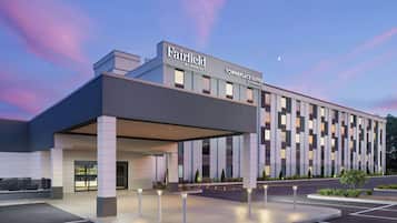 A modern hotel with a covered entrance, a parking lot, and a sign indicating it's a Marriott property.