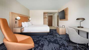Una habitación de hotel con cama, escritorio, silla, televisión y armario.