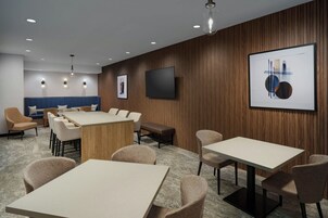 Una sala de conferencias con una gran mesa, varias sillas, un sofá y un televisor de pantalla plana montado en la pared.