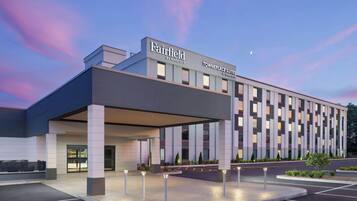 A modern hotel with a covered entrance, multiple floors, and a parking lot.