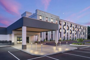 A modern hotel with a covered entrance, multiple floors, and a parking lot.