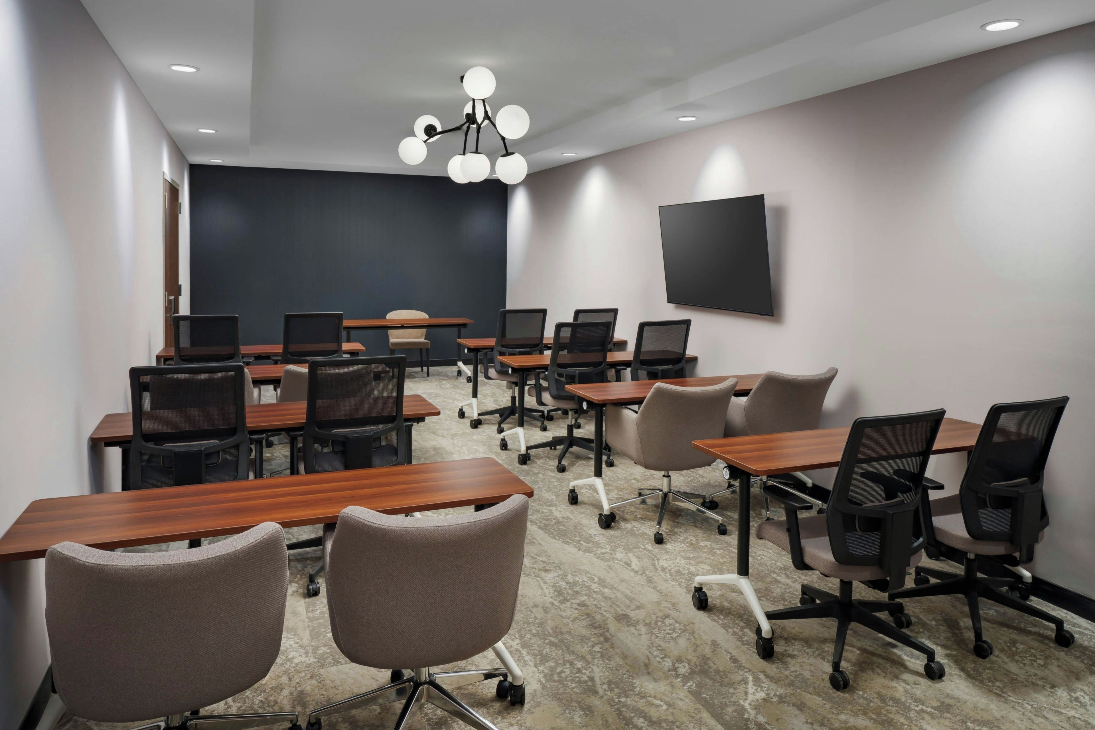 A conference room with a large blackboard, multiple tables, and chairs.