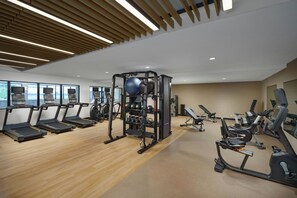 Ein modernes Fitnessstudio mit Laufbändern, Kraftgeräten und Übungsbällen.