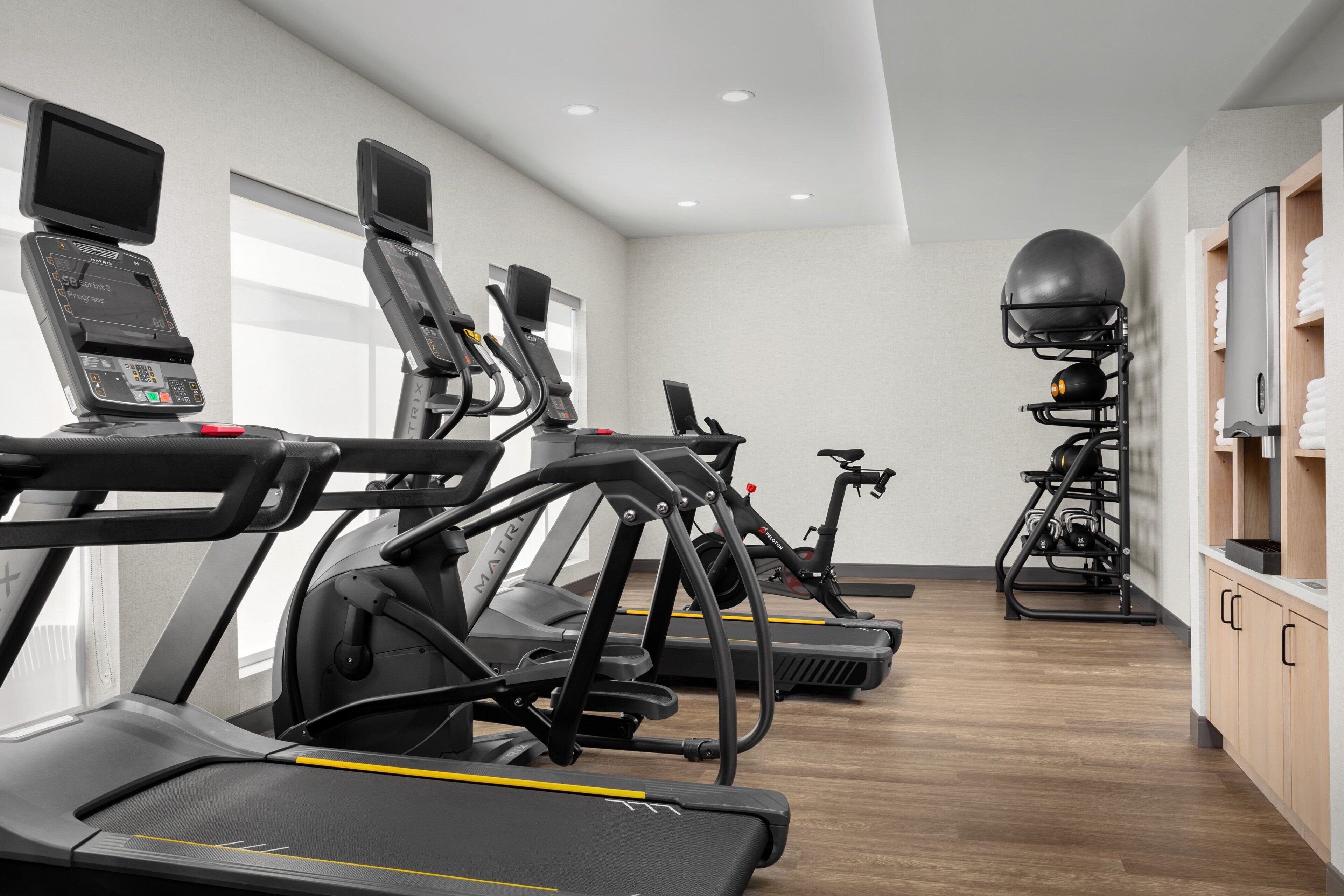 Un gimnasio con cintas de correr, bicicletas estáticas y una zona de pesas.