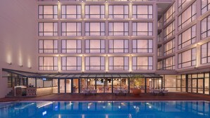 A modern hotel with a pool, outdoor seating, and multiple floors. - Courtyard By Marriott Goa Colva (Colva)