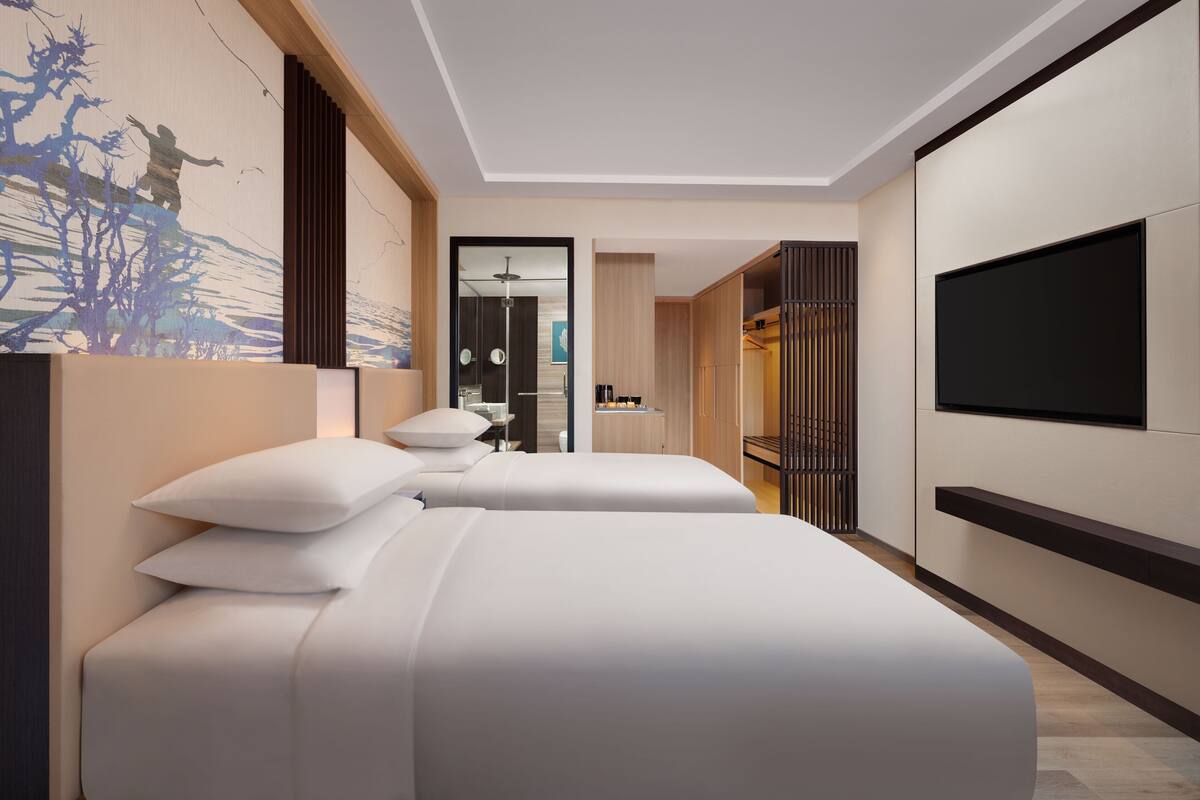 Et moderne hotelværelse med to senge, et fjernsyn og udsigt til gangen.