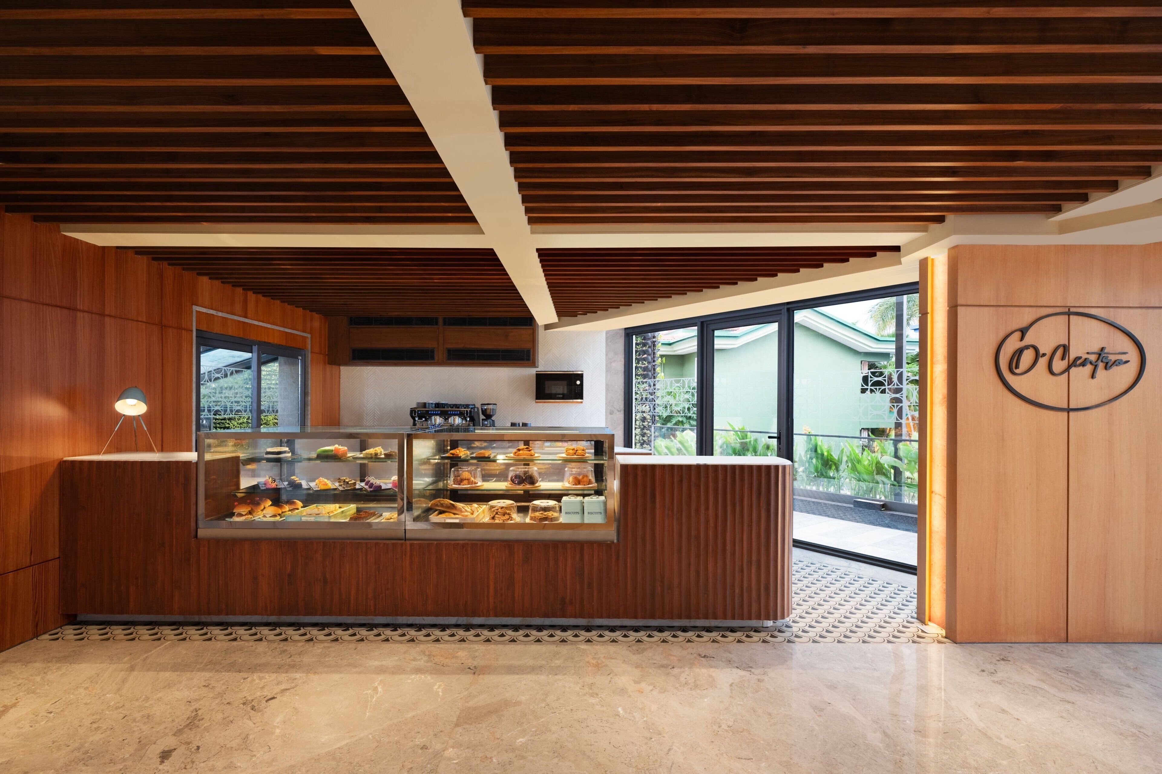 A modern bakery with a wooden counter displaying pastries, a coffee machine, and a glass display case.