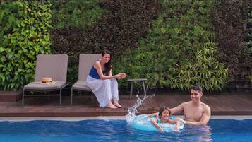 Relax by the pool surrounded by lush greenery and comfortable lounge chairs.