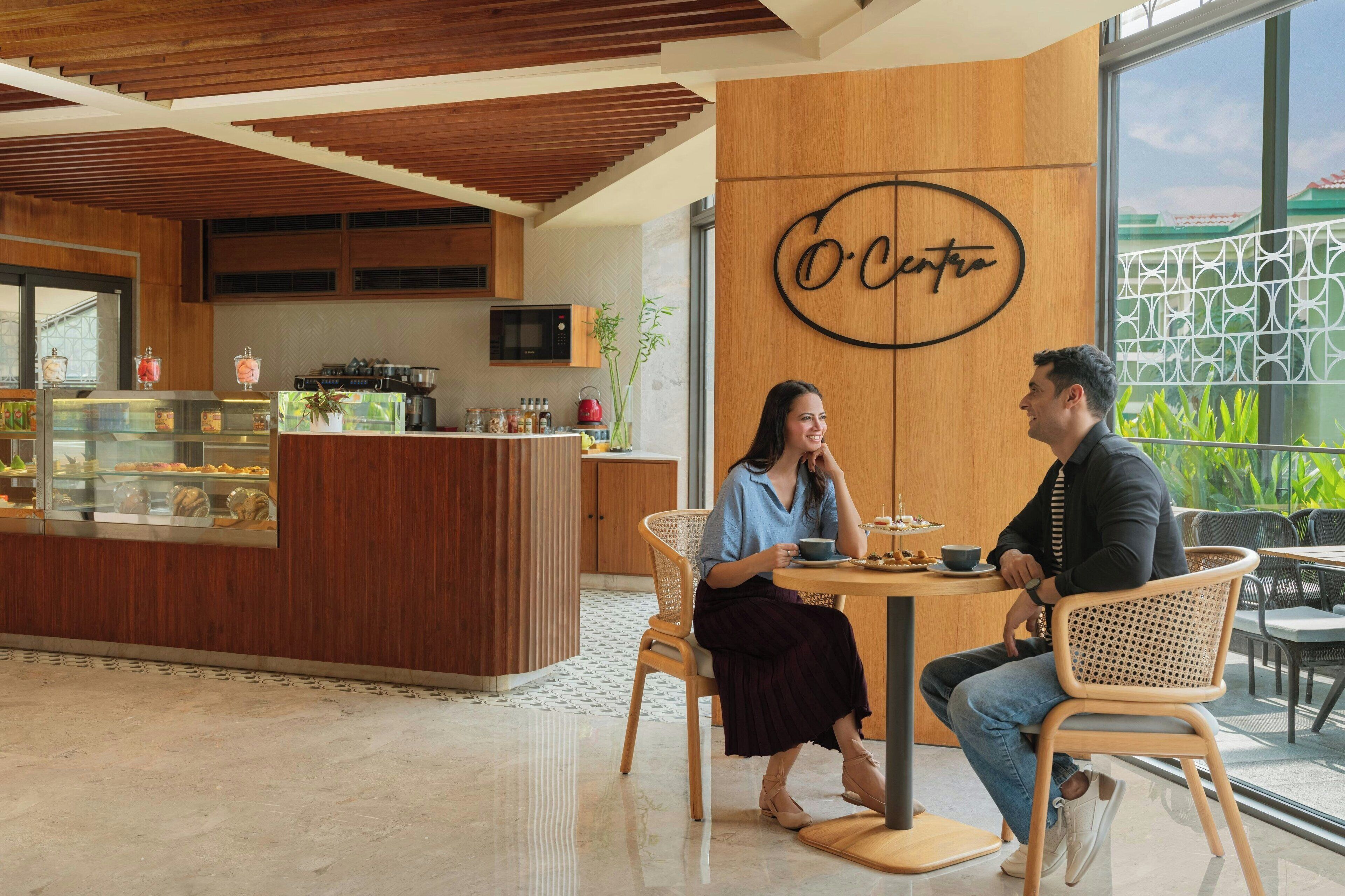 Una cafetería con interior de madera, una barra con productos de repostería y un letrero que dice "O Centro".