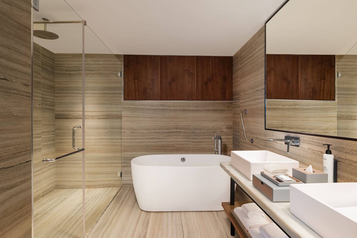 A modern bathroom with a freestanding bathtub, a glass-enclosed shower, and a vanity with a large mirror.