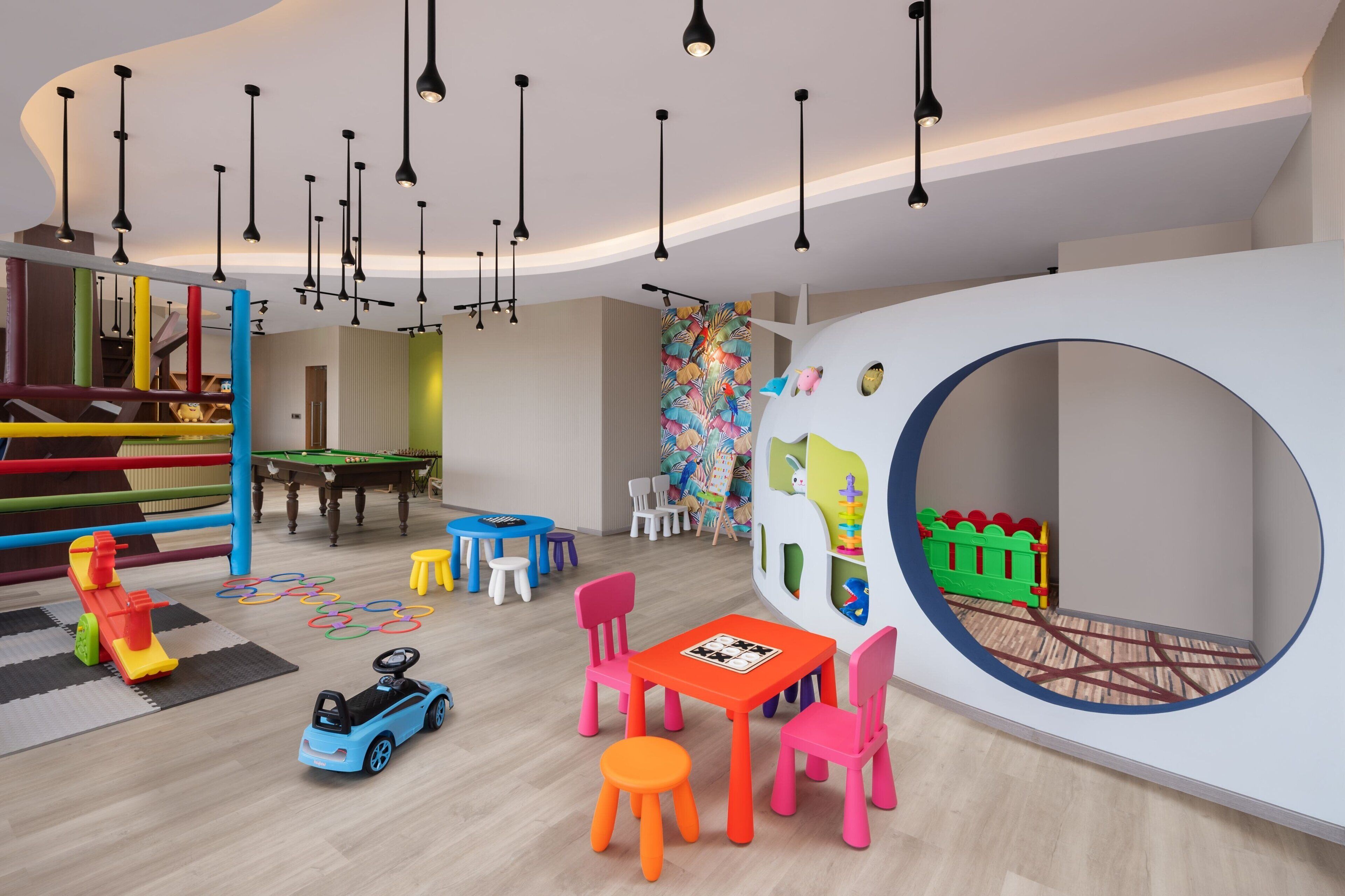 A children's play area with colorful play structures, a pool table, and a circular play zone.