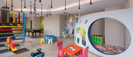 Zona de juegos infantiles con estructuras de juego coloridas, una mesa de billar y un área de juegos circular.