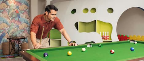 A pool table with balls, a person leaning over it, and a colorful wall with a star and a large paw print design.