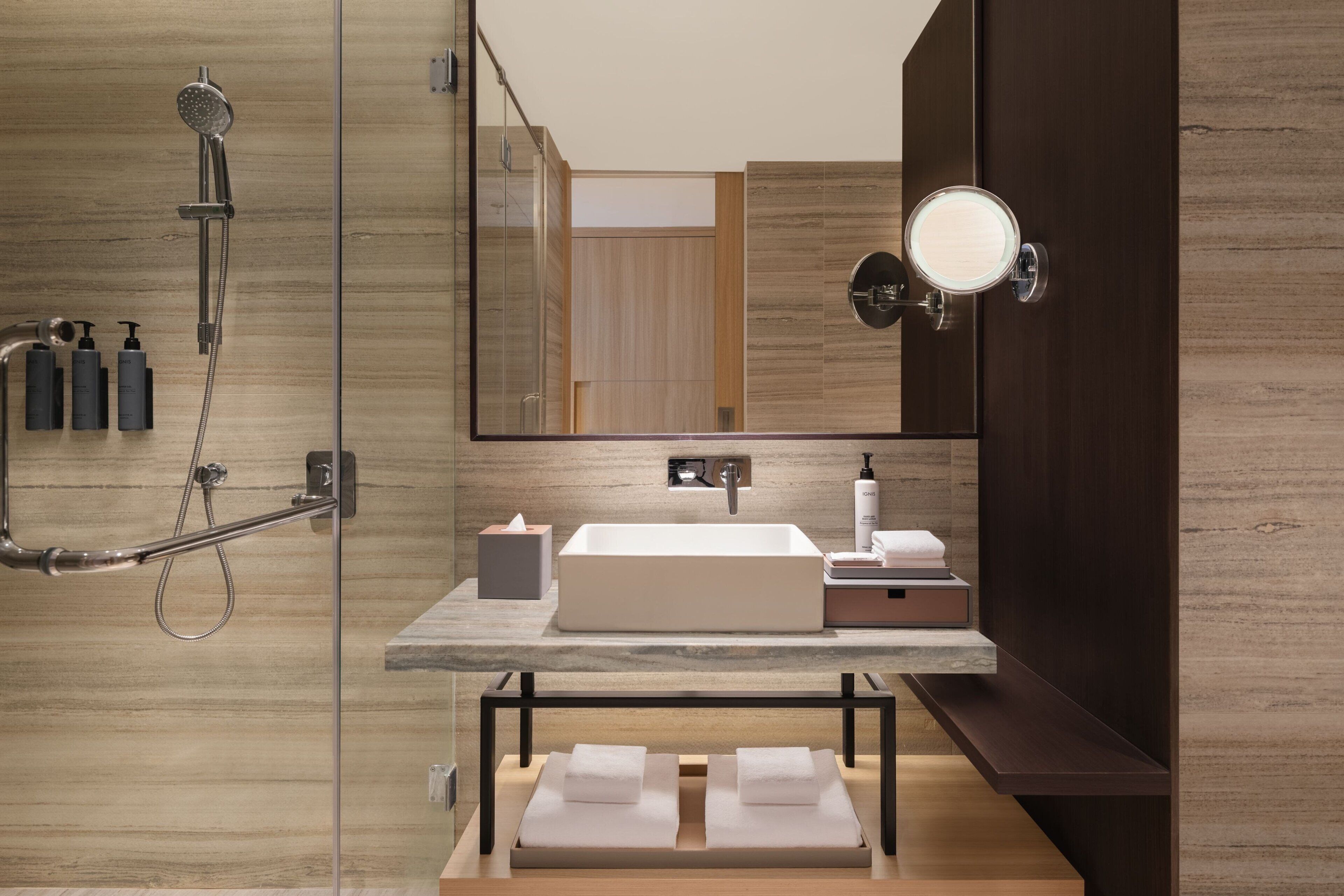 Un baño moderno con un espejo grande, un lavamanos integrado, una ducha y un tocador con artículos de aseo.