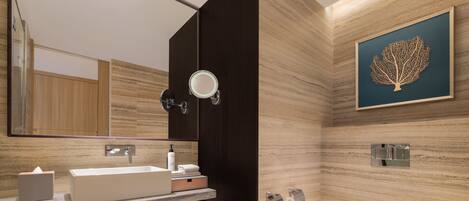 A modern bathroom with a large mirror, a sink, a toilet, and a bench.