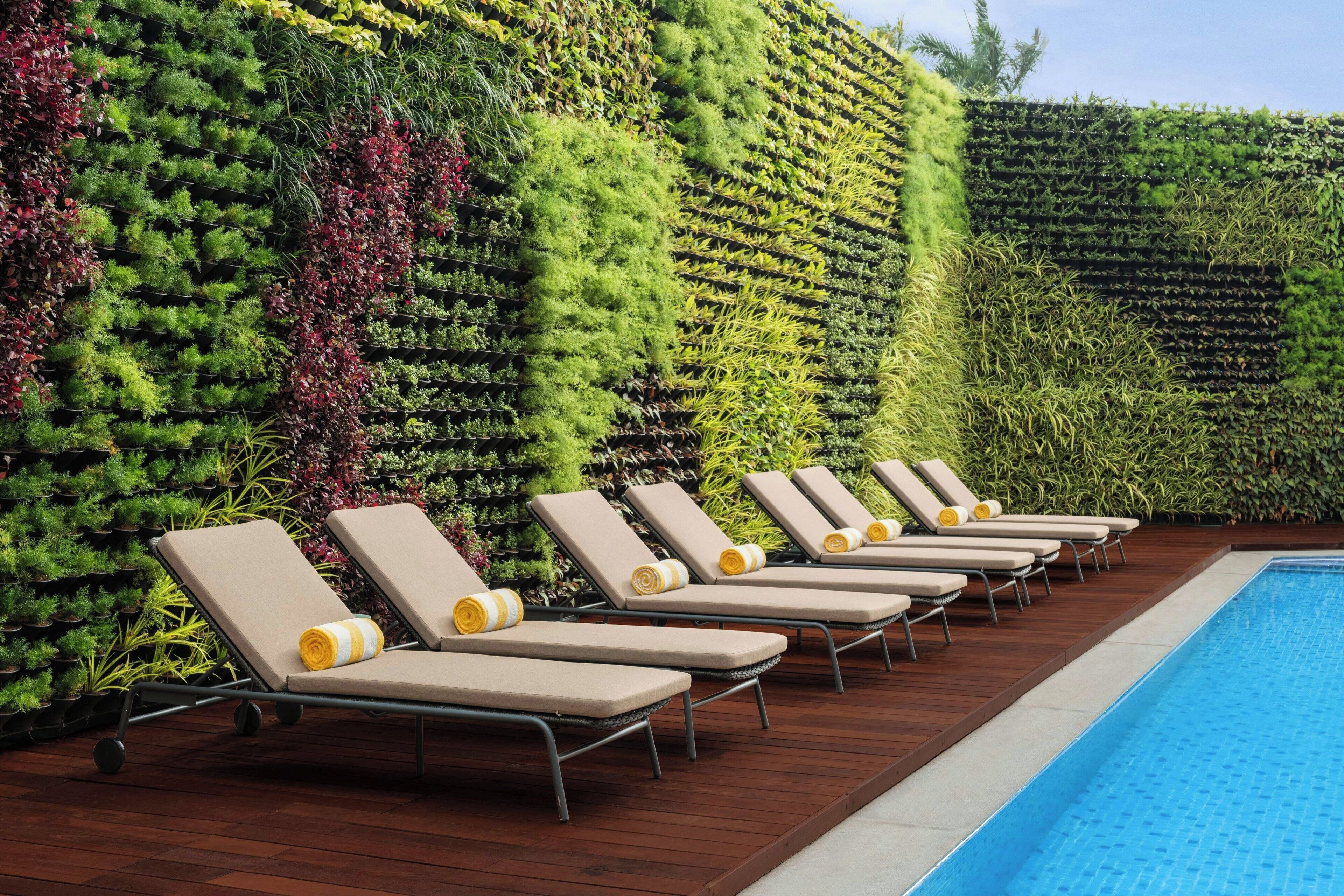 Zona de piscina con sillones de descanso y un jardín vertical.