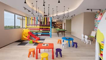Zona de juegos infantiles con mobiliario colorido y un tobogán.