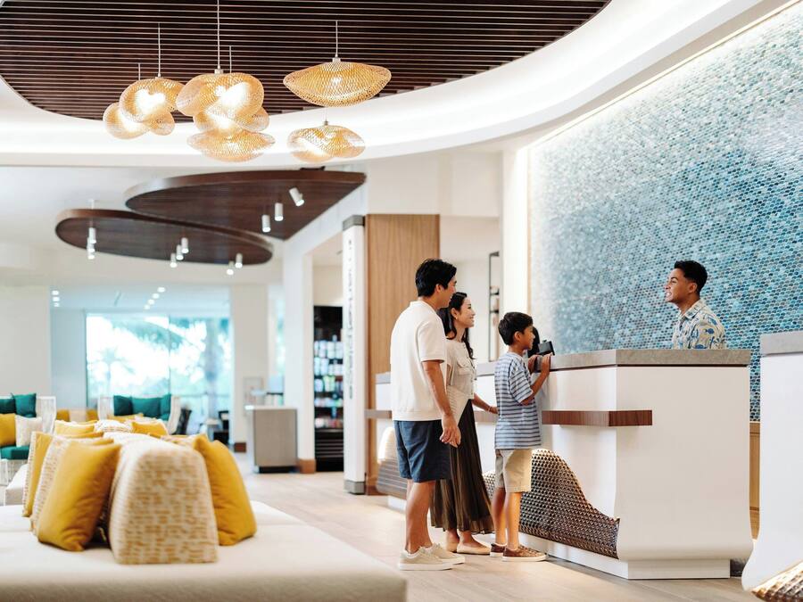 Un moderno vestíbulo de hotel con una recepción, zona de estar y un techo decorativo.