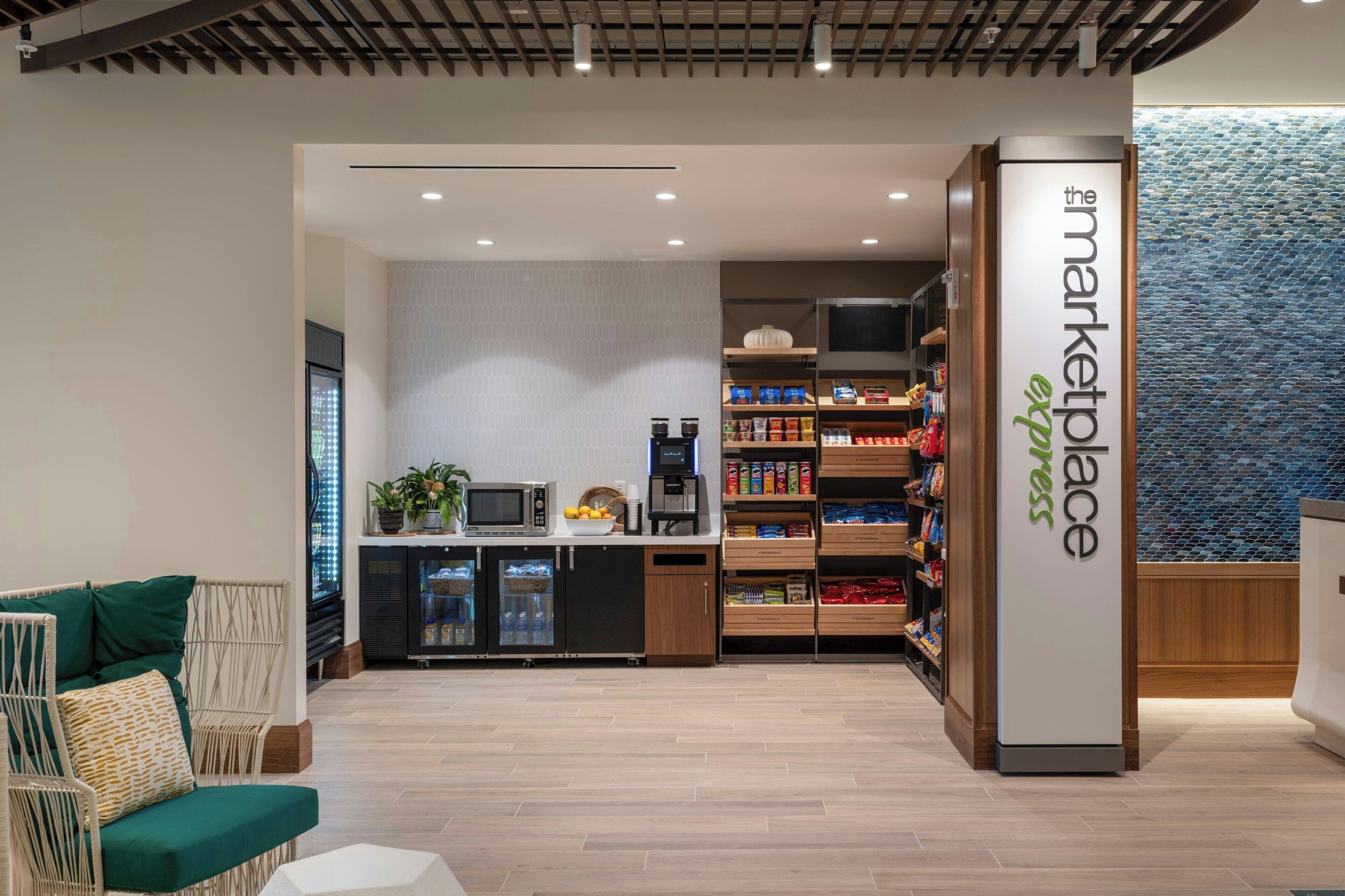 Um interior moderno com cozinha compacta, área de estar e um grande letreiro vertical com a inscrição 'the marketplace express'.