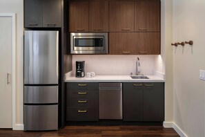 A modern kitchen with stainless steel appliances, dark cabinetry, and a white countertop.