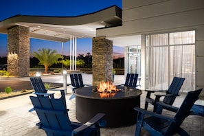 An outdoor seating area with a fire pit, stone pillars, and blue chairs. - Fairfield By Marriott Inn & Suites Waycross (Waycross)