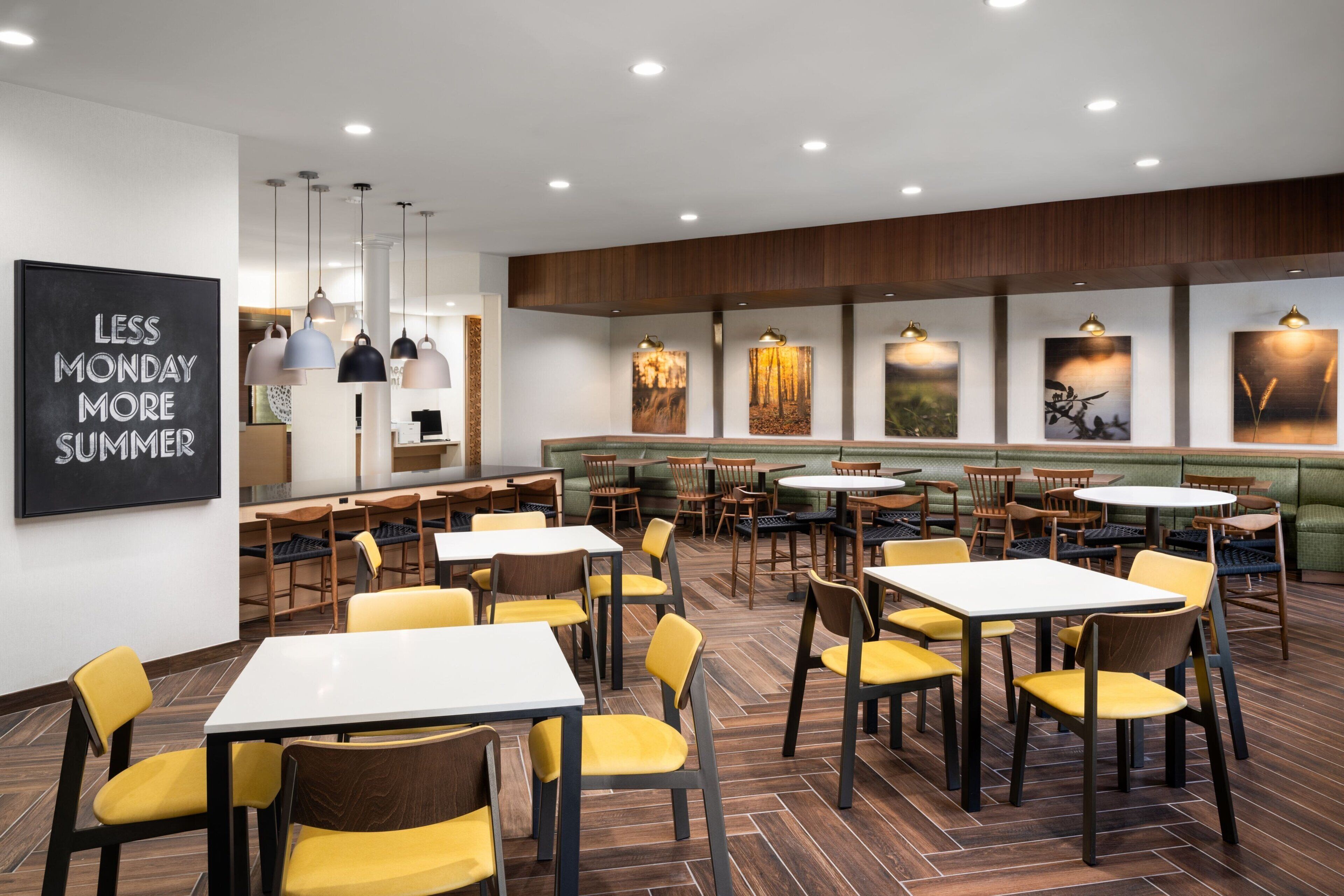 A restaurant with tables and chairs, a blackboard with text, and artwork on the walls.