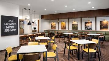 A restaurant with tables and chairs, a blackboard with text, and artwork on the walls.