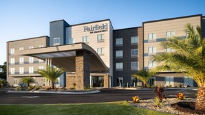 Un hotel Fairfield by Marriott con un diseño moderno, que cuenta con una entrada cubierta y un camino de entrada arbolado.