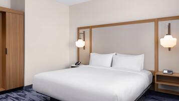 A hotel room with a large bed, wooden headboard, bedside tables with lamps, and a wardrobe.
