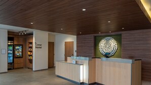 A reception area with a wooden reception desk, a 'Corner Market' sign, and a decorative wall piece. - Fairfield by Marriott Inn & Suites Southaven Snowden Grove (Southaven)