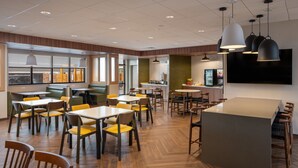 A modern restaurant with wooden flooring, yellow and brown chairs, and a central island with seating. - Fairfield by Marriott Inn & Suites Southaven Snowden Grove (Southaven)