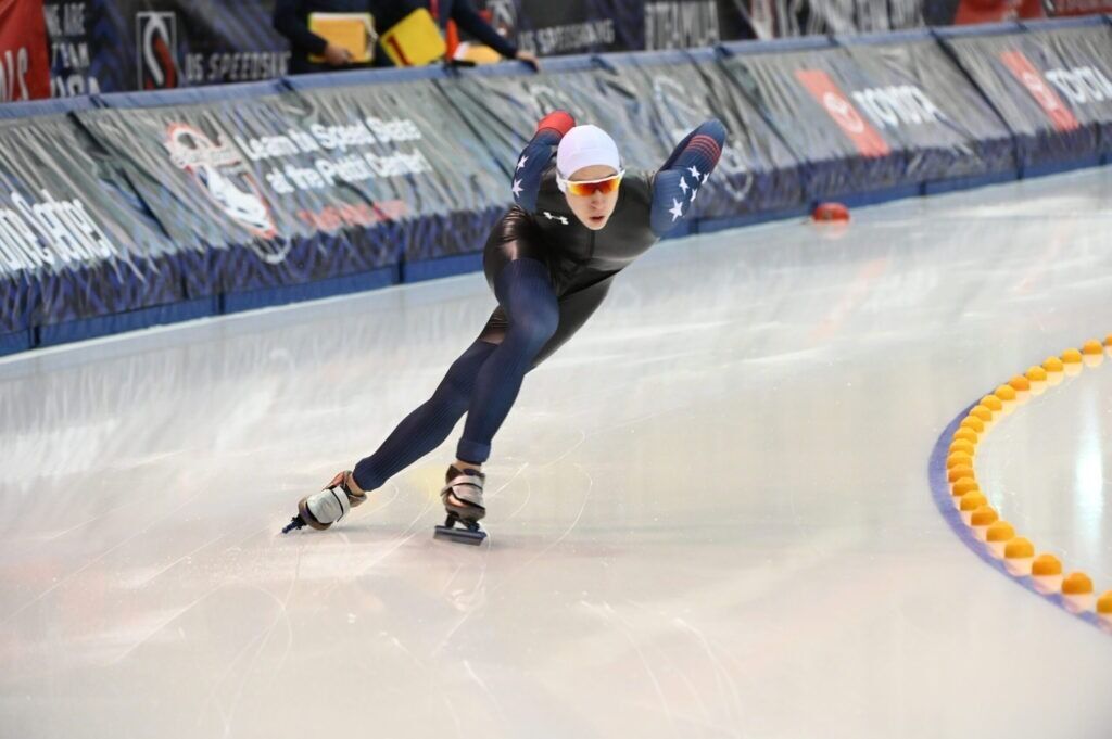 A speed skater in motion on an indoor ice track.