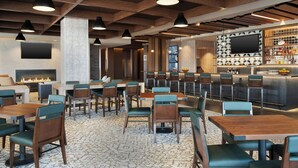 Een restaurant met houten tafels en stoelen, een bar en een flatscreen televisie aan de muur.