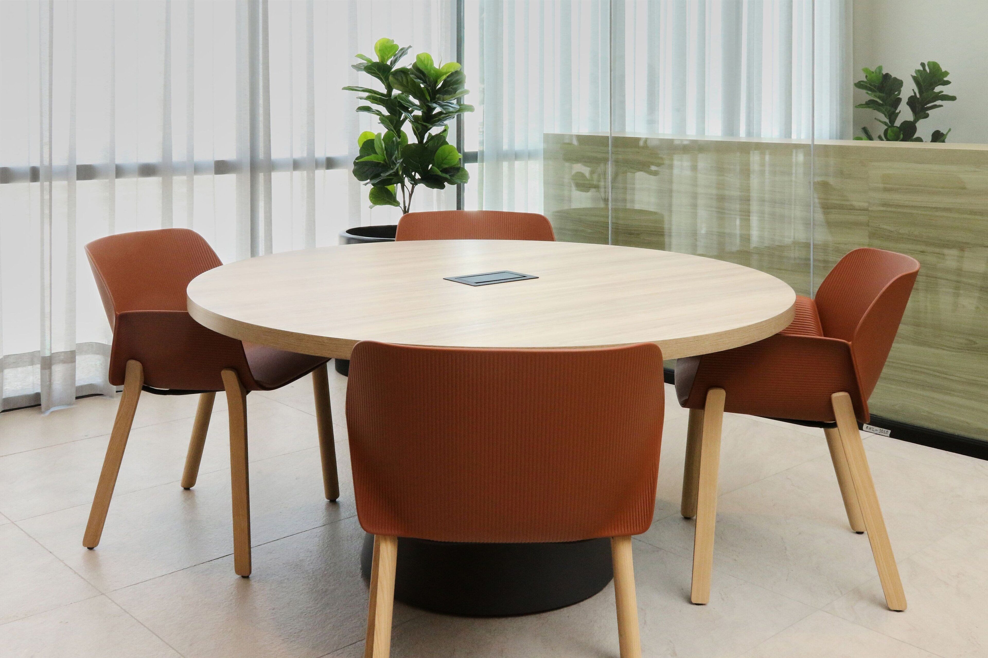 Une table ronde avec quatre chaises marron, une petite plante en pot et un téléphone intelligent posé sur la table.
