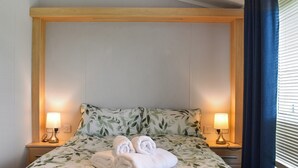 A neatly made bed with a leaf-patterned bedspread, two rolled towels, and two bedside lamps. - Meadows Lodge - UK46825 (Moota, near Cockermouth and North Lakes)