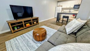 A modern living room with a sofa, ottoman, and entertainment unit. - Cozy 1/1 Walking distance to Doak Campbell Stadium and campus (Tallahassee)