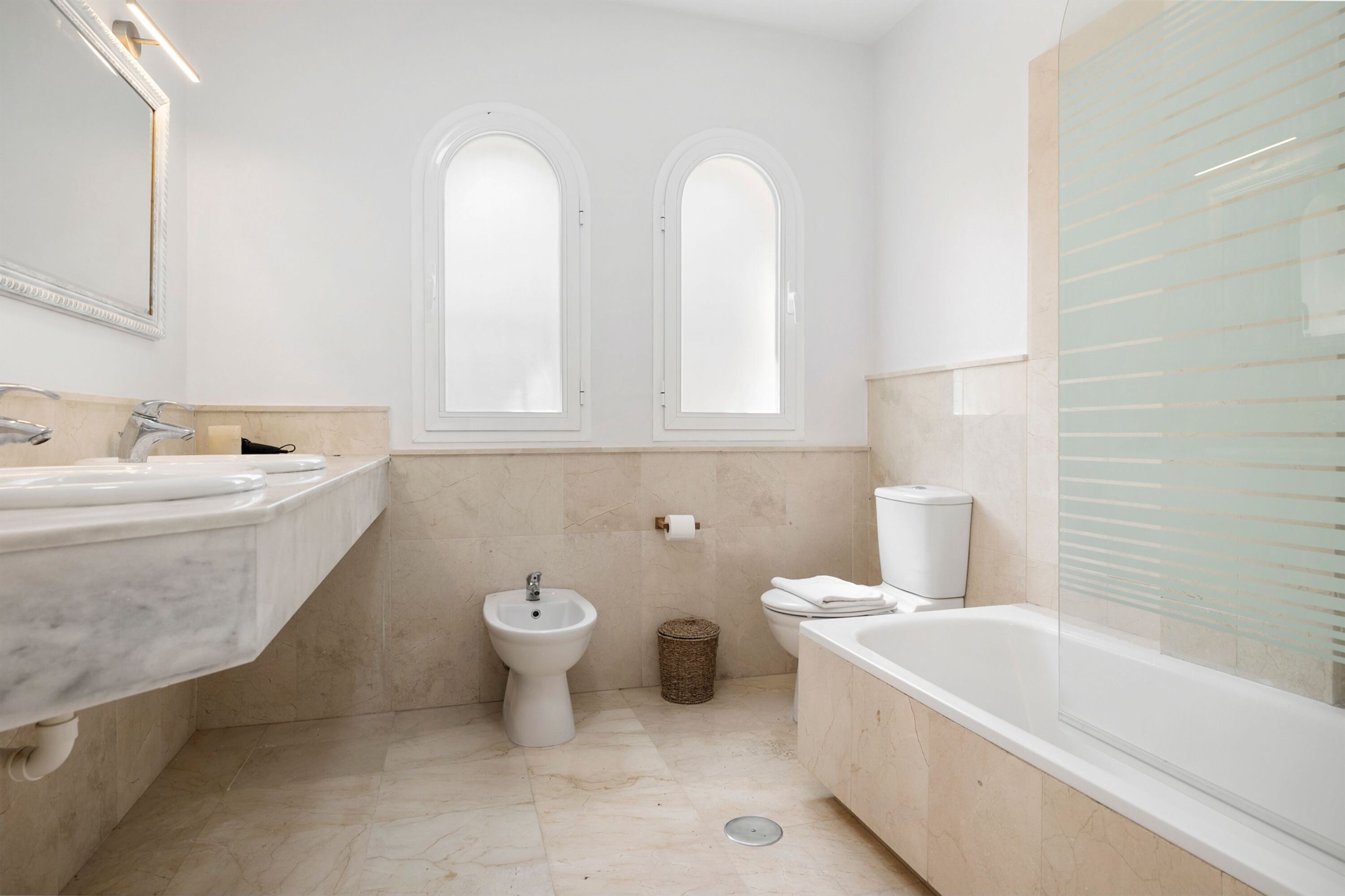 A modern bathroom with a marble sink, bidet, toilet, and bathtub.