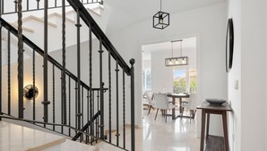 Una escalera con barandales negros que conduce a un comedor con mesa y sillas.