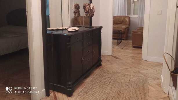 Un dormitori amb un llit, una petjaina, un mirall i una finestra amb cortines.