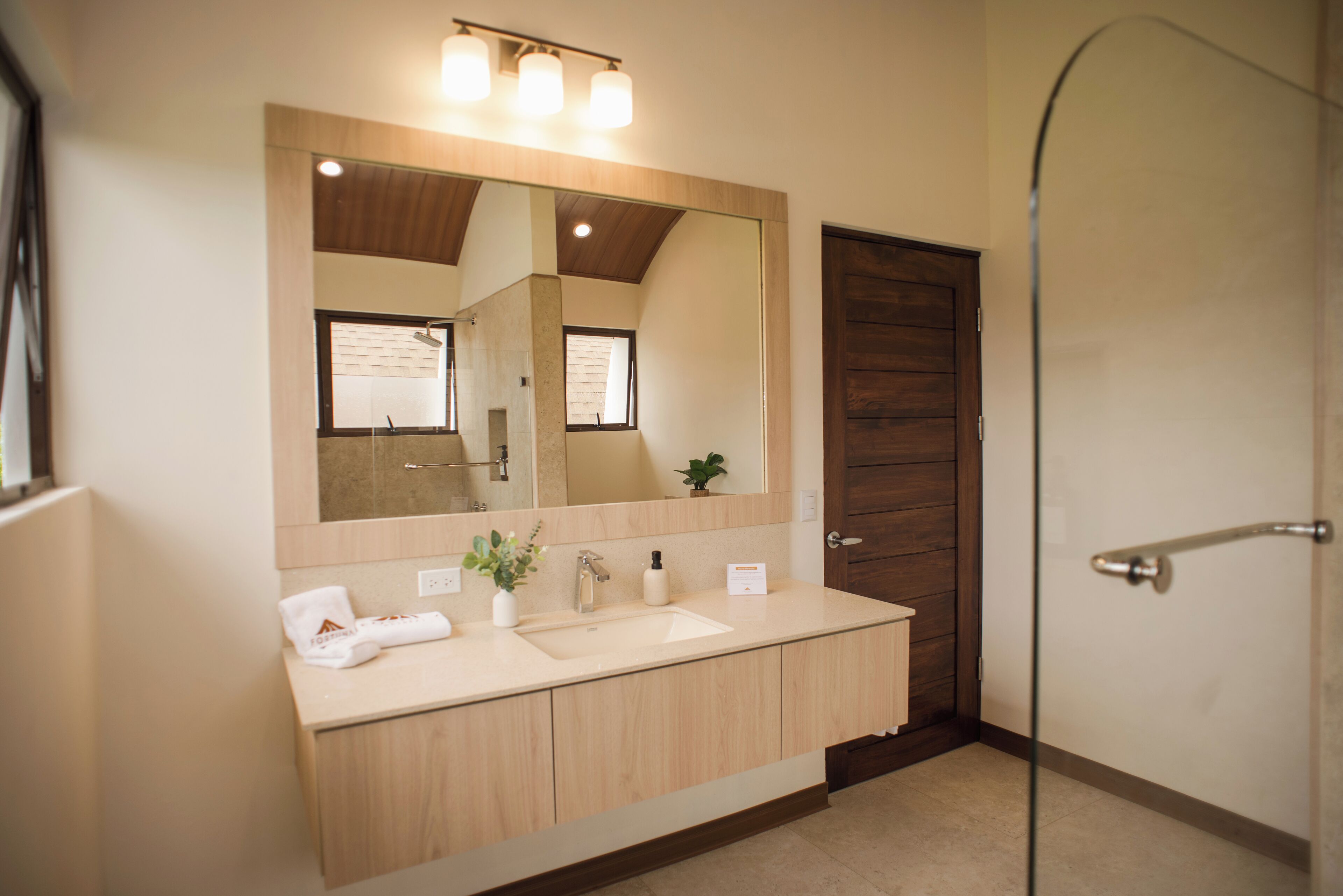 Een moderne badkamer met een grote spiegel, een wastafel en een douche.