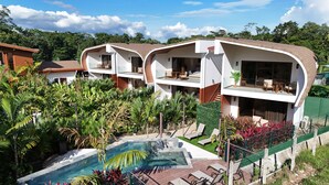 A modern resort with multiple two-story buildings, a swimming pool, and lush tropical landscaping. - Fortuna Retreat (La Fortuna)