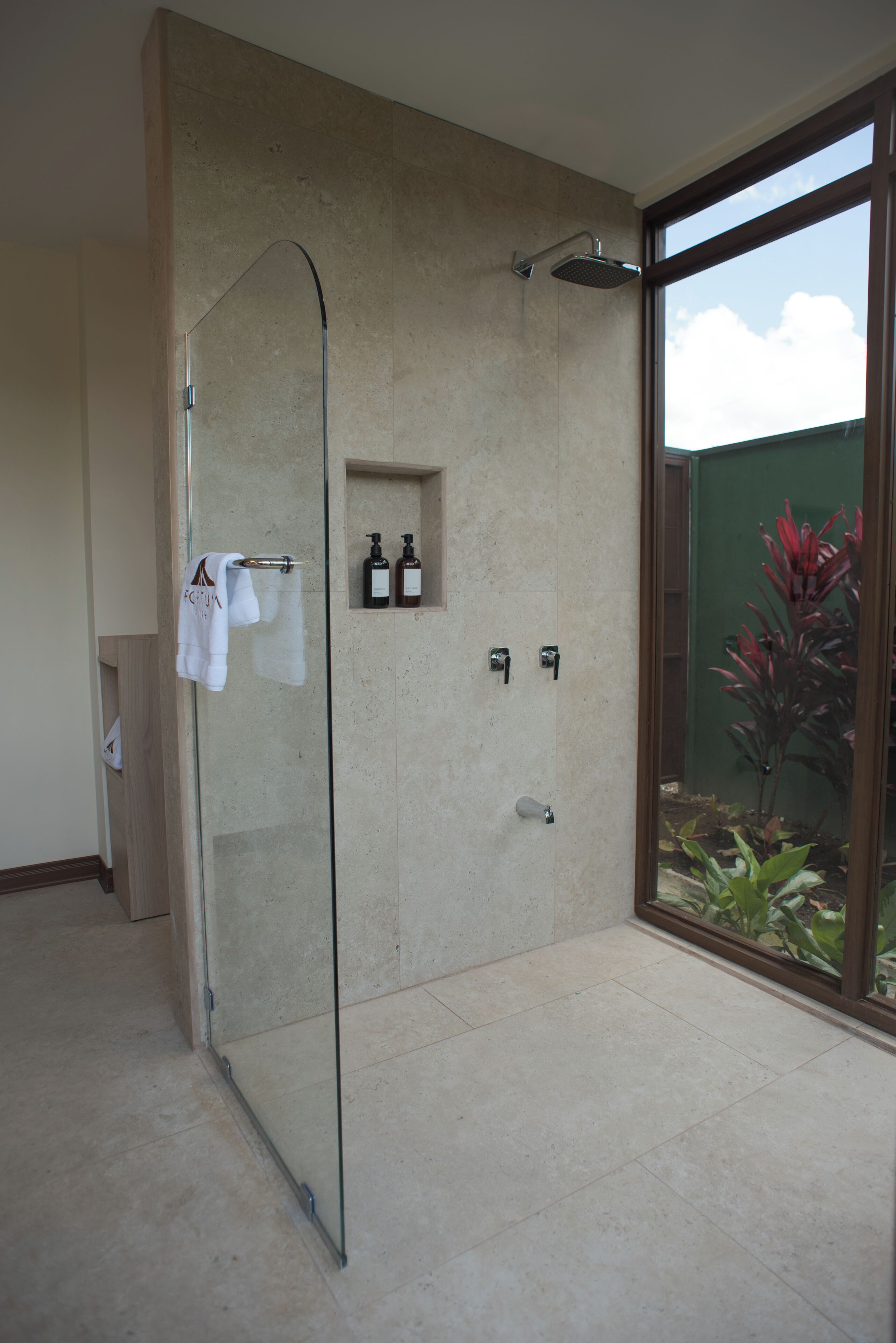 Ein modernes Badezimmer mit Duschkabine aus Glas, Handtuchhalter und einer kleinen Ablage für Toilettenartikel.