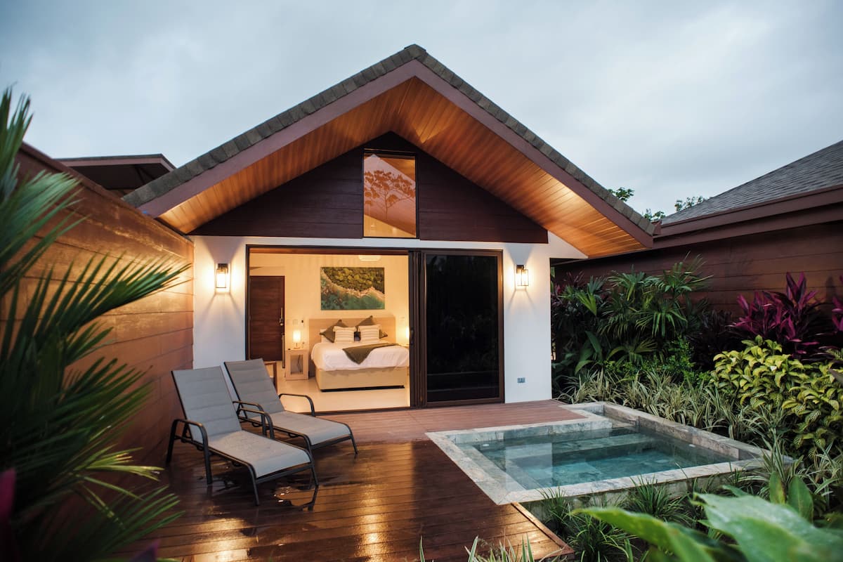 A modern villa with a bedroom, a balcony, and a swimming pool.