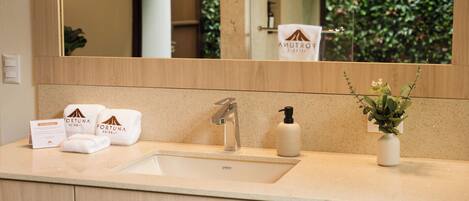 A bathroom with a sink, mirror, towel rack, and a potted plant.