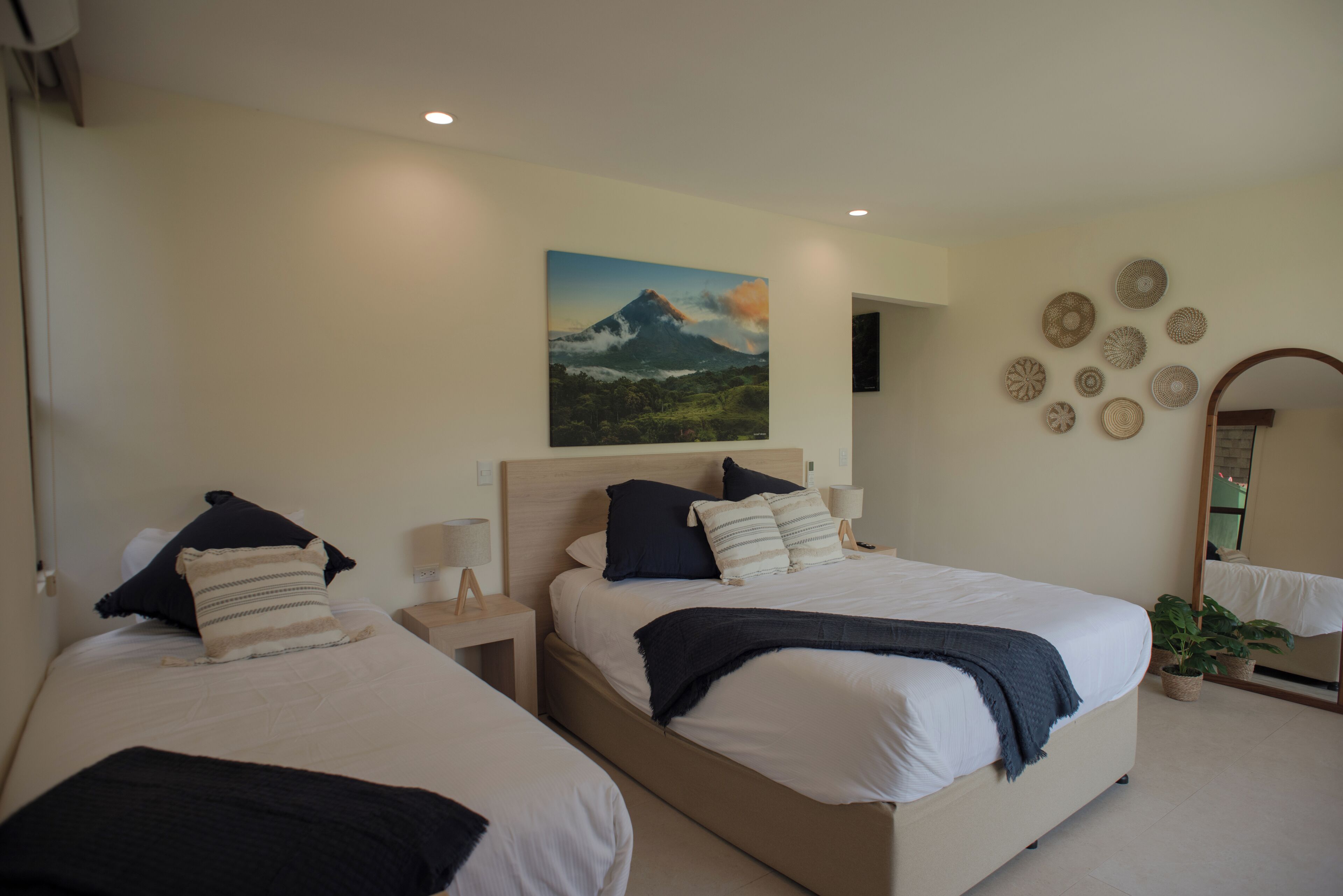 Habitación de hotel con dos camas, un cuadro de una montaña y una pared decorada con platos.