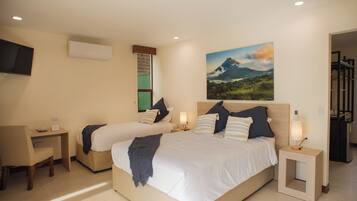 Habitación de hotel con dos camas, un escritorio, una silla, un televisor y un cuadro en la pared.