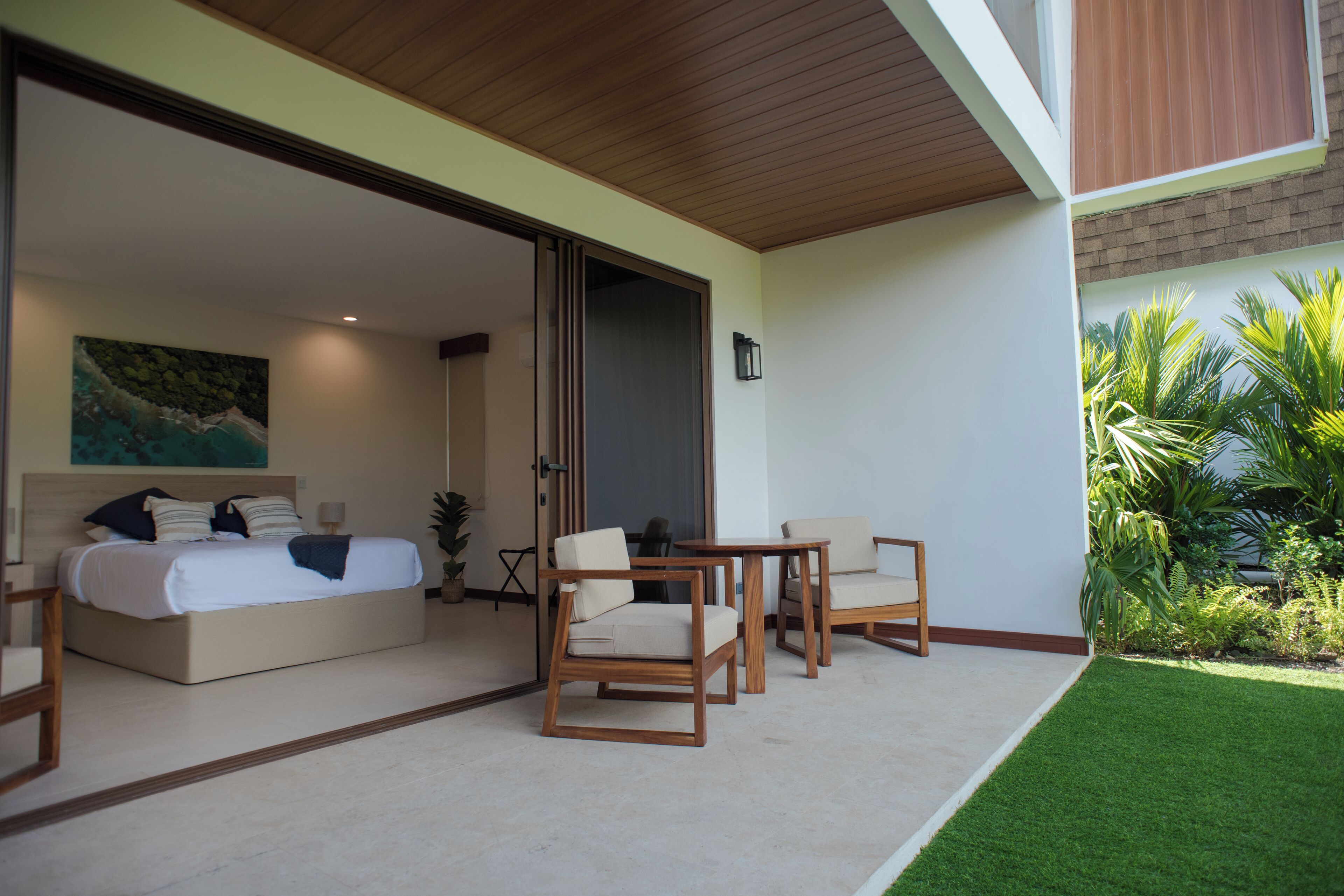 A modern bedroom with a large bed, two chairs, and a small table.