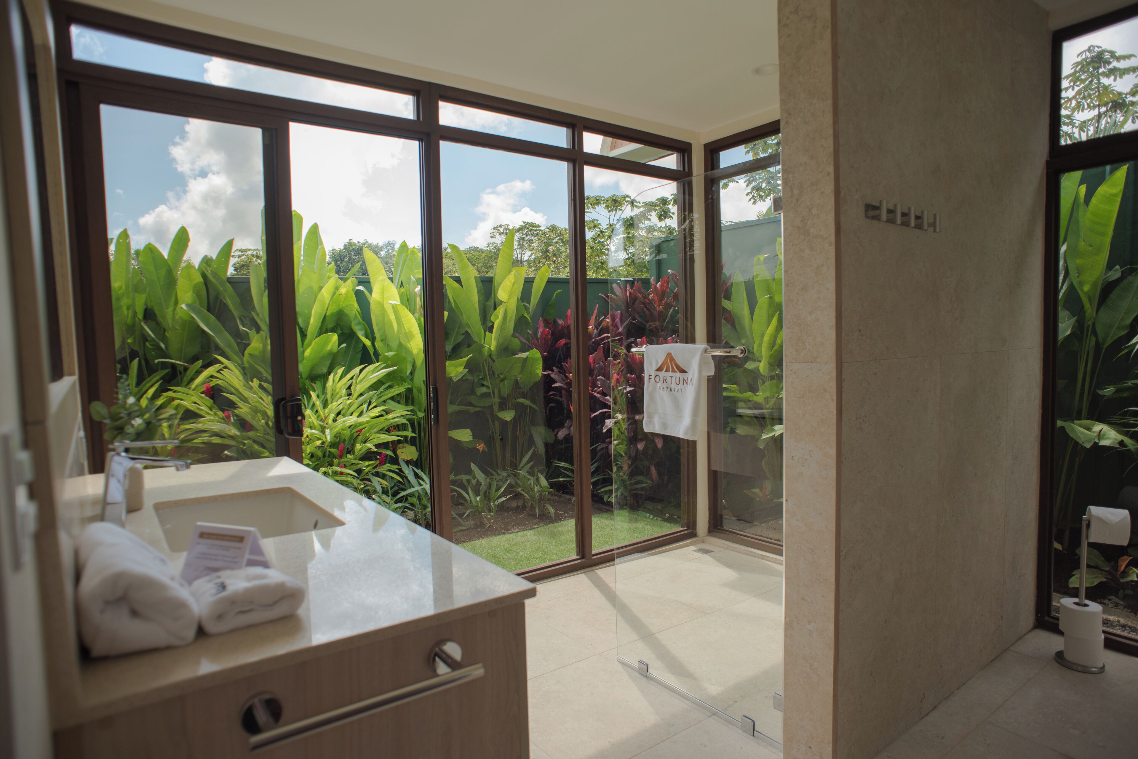A modern bathroom with a large window, a sink, and a towel rack.